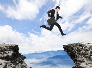 businessman jumping over danger precipice