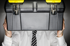 Man wearing tie holding toolbox in front of face