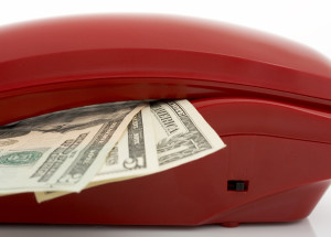Photo of a telephone and dollars over a white background